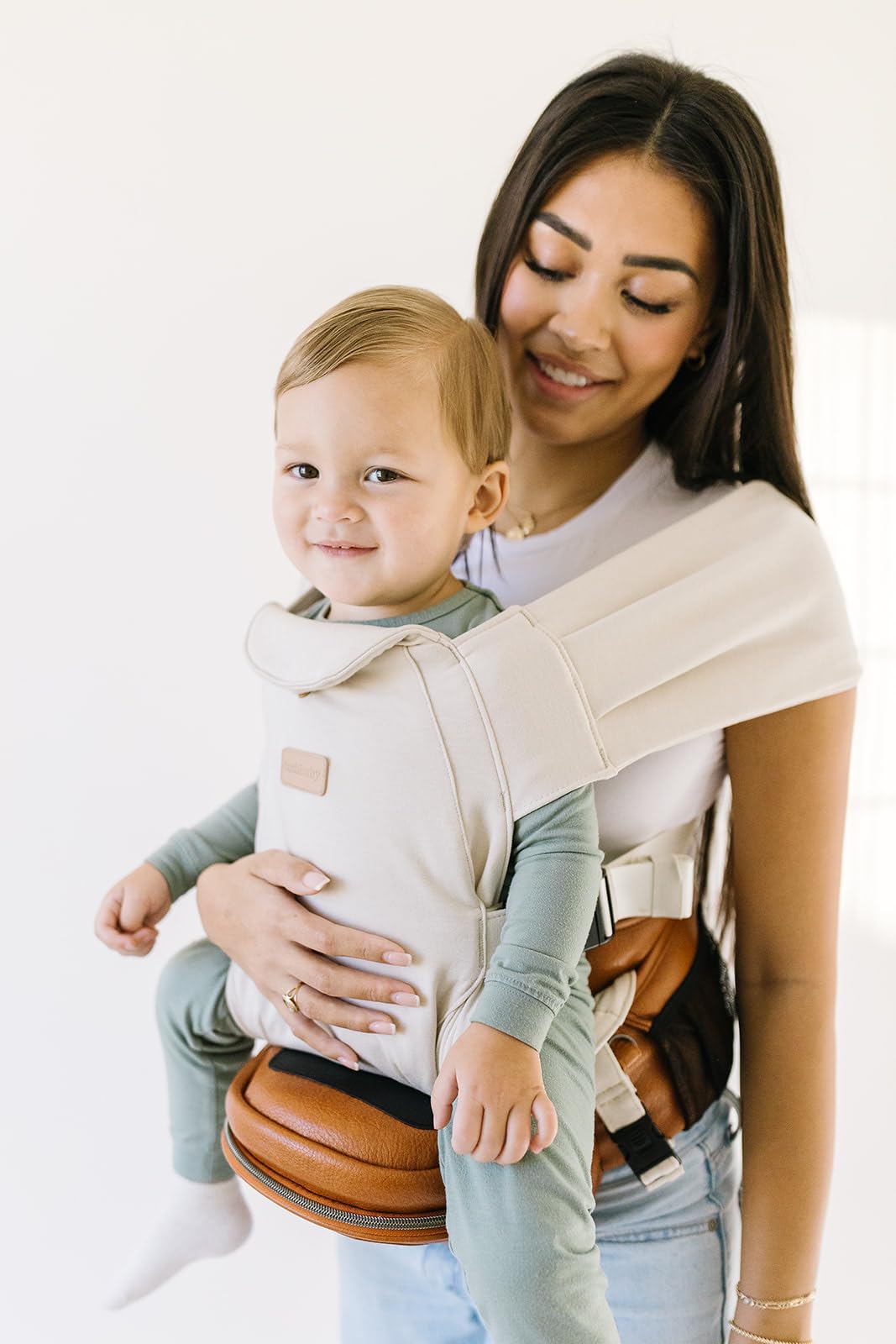 Tushbaby Portabebés Manos Libres 2 en 1 con Soporte Lumbar, Asiento Ergonómico y Almacenamiento Integrado, Para Niños de 5.4 a 20 kg En Piel Vegana y Color Crema