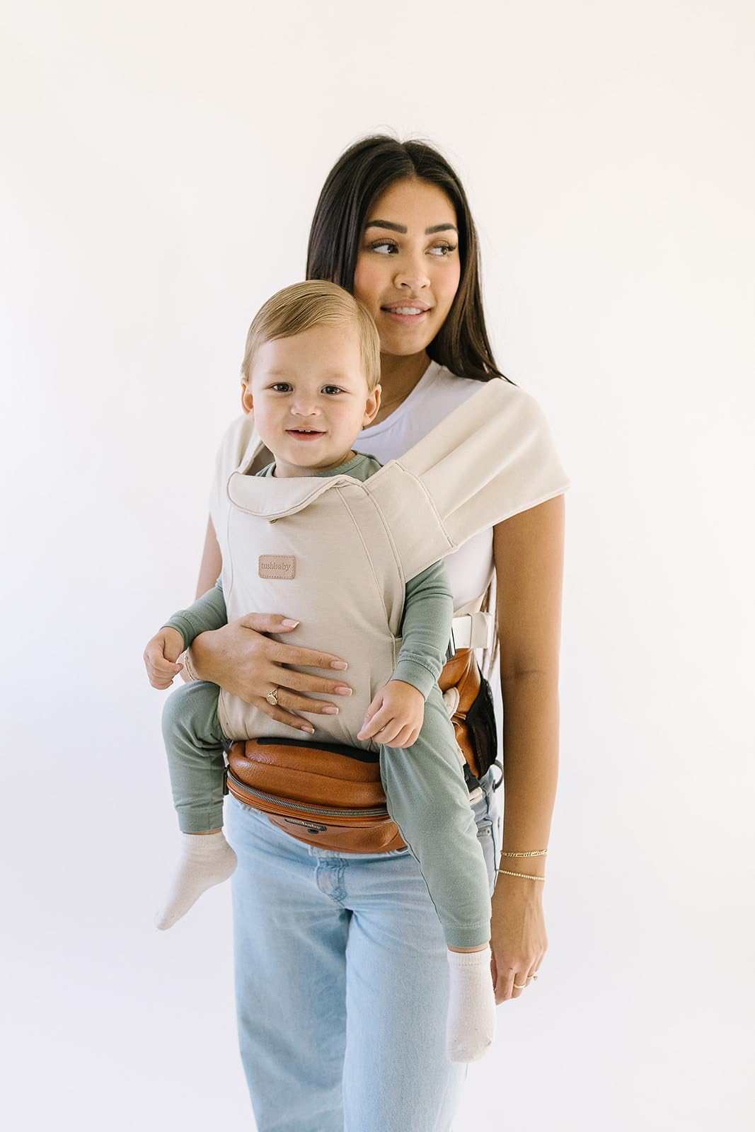 Tushbaby Portabebés Manos Libres 2 en 1 con Soporte Lumbar, Asiento Ergonómico y Almacenamiento Integrado, Para Niños de 5.4 a 20 kg En Piel Vegana y Color Crema