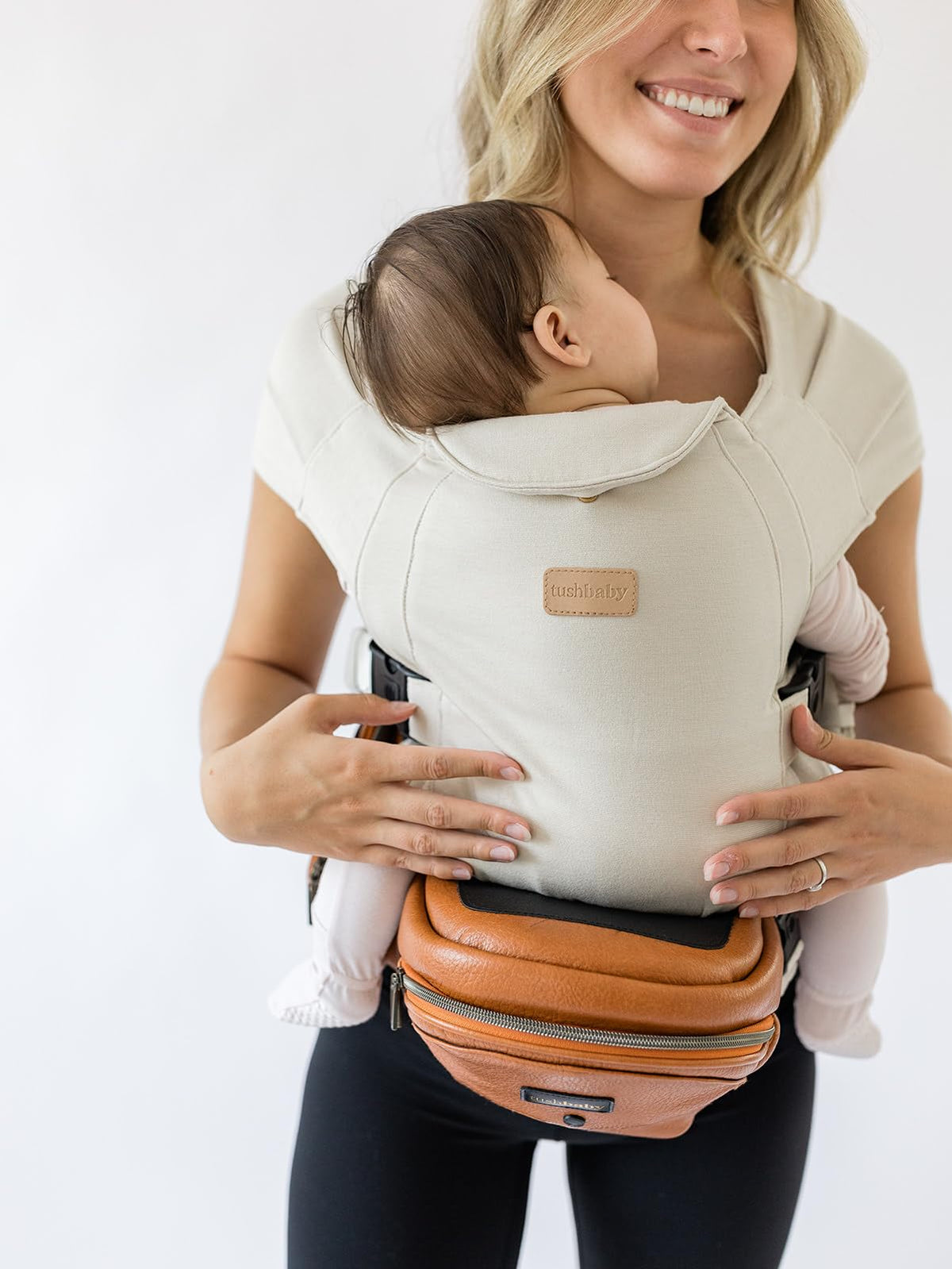 Tushbaby Portabebés Manos Libres 2 en 1 con Soporte Lumbar, Asiento Ergonómico y Almacenamiento Integrado, Para Niños de 5.4 a 20 kg En Piel Vegana y Color Crema