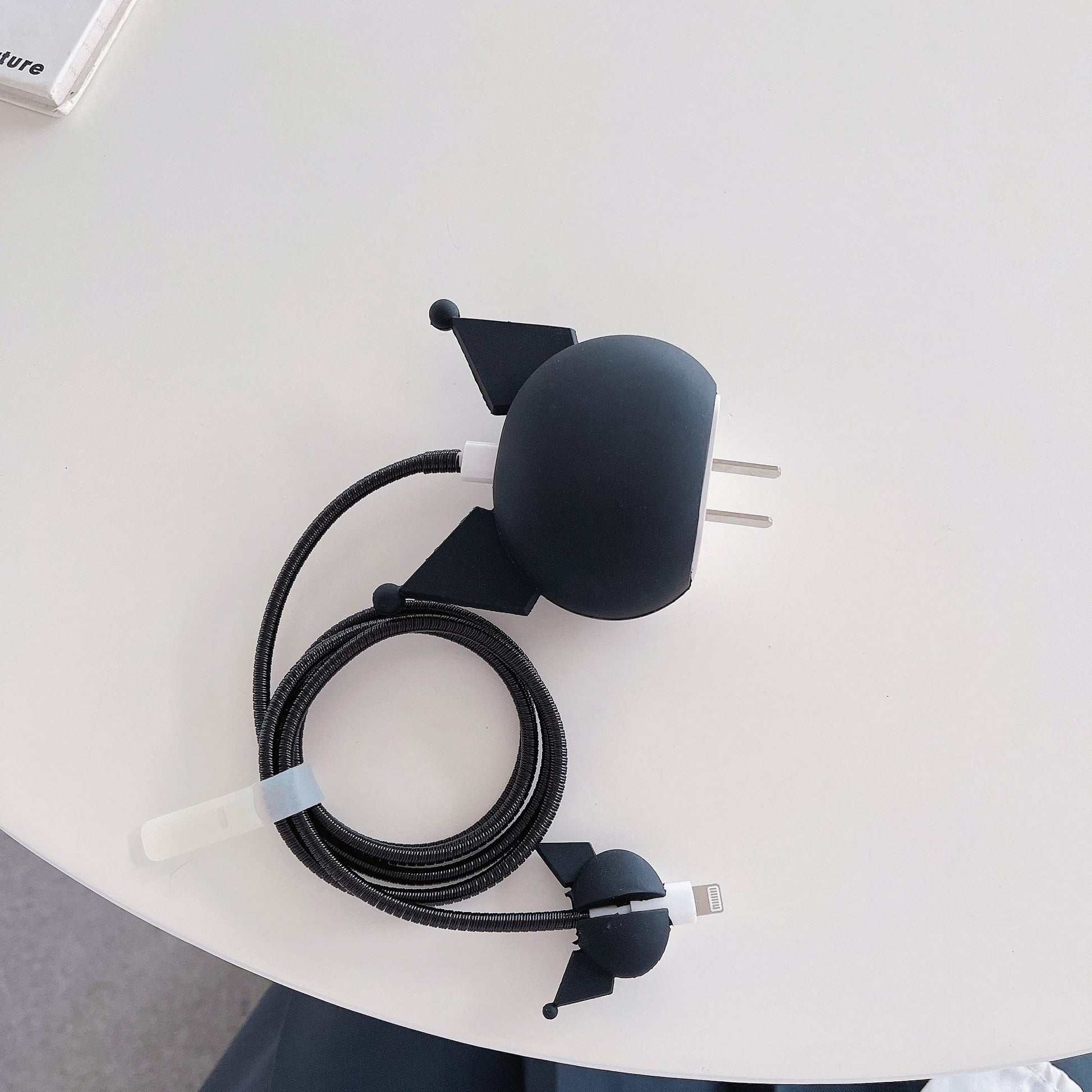 Tospania - Bonita funda protectora 3D para cargador con diseño de caricaturas, compatible con adaptador de corriente USB-C de 20 W de Apple y cable Lightning (Kuro negro)
